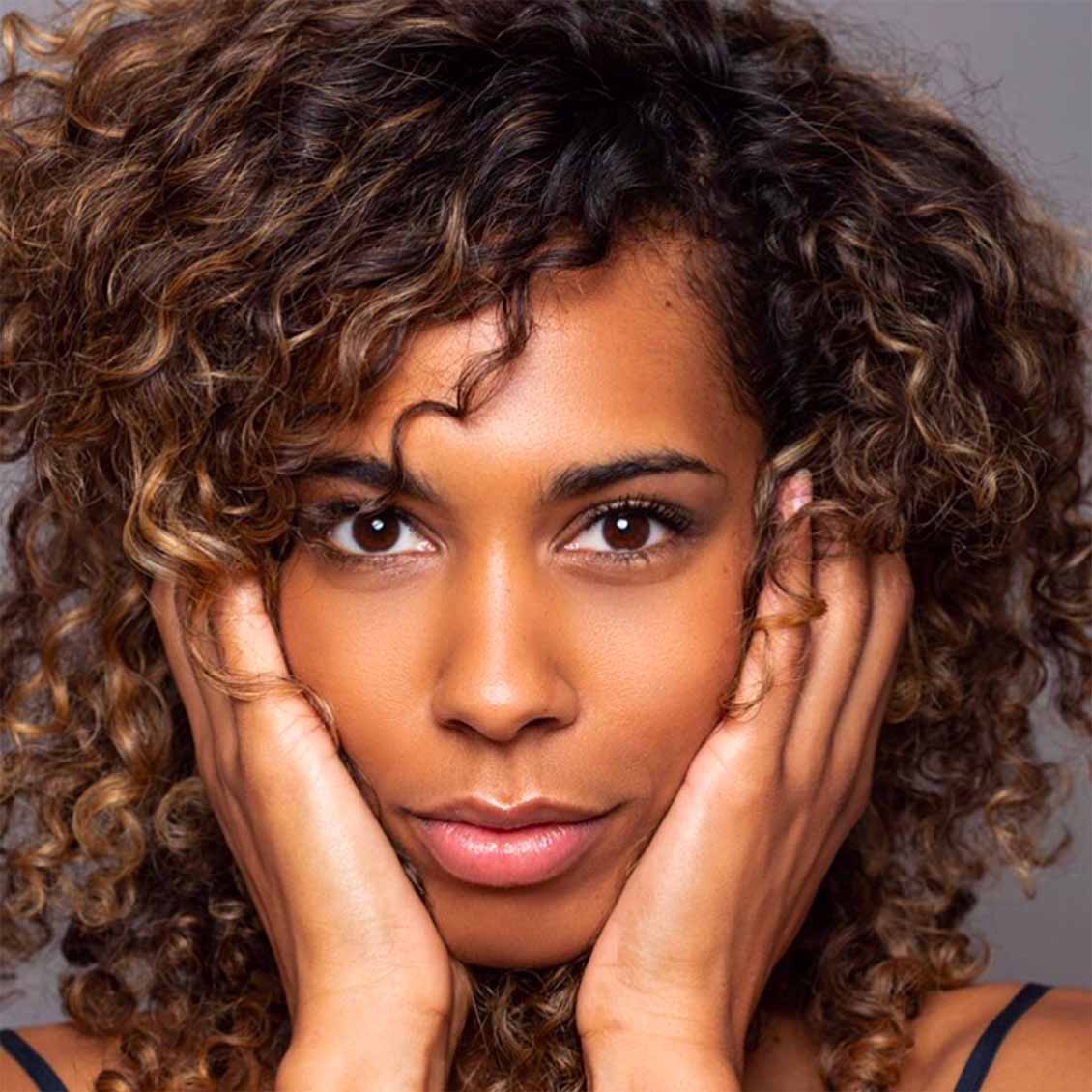 Une femme aux cheveux bouclés parfaitement définis, illustrant les résultats de la routine détox pour cheveux secs.