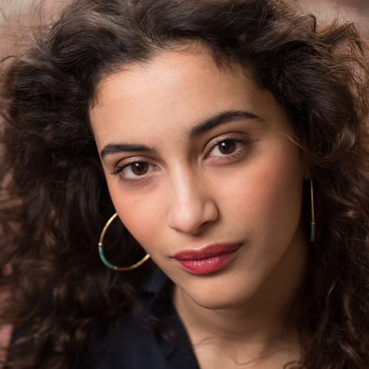 Portrait d’une femme aux cheveux bouclés illustrant une routine de printemps pour cheveux bouclés, avec une chevelure naturelle et bien définie.